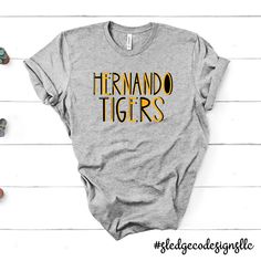 HERNANDO TIGERS LETTERED | CUSTOM UNISEX TSHIRTS Cheer on your team in style with this TIGERS TSHIRT! Show your team spirit, this one-of-a-kind hand-drawn crewneck is sure to impress! Please allow 2-3 WEEKS (NOT INCLUDING) business days for processing - THESE ARE MADE TO ORDER! If preorder - these we process after preorder date. - You will be notified by email on when your order is ready! We are located in Olive Branch. All our items are completely custom, and made to order for a unique style! W Tiger Shirts, School Spirit Wear, Tiger Shirt, State School, Dress Appropriately, Spirit Wear, Co Design, Olive Branch, Unisex Tshirt