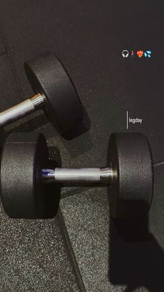 two black dumbbells sitting on top of a gray floor next to each other