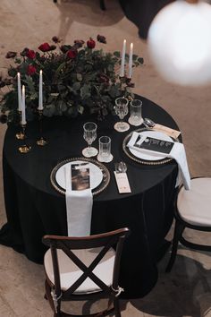 the table is set with black linens and gold trimmings, white napkins and candles