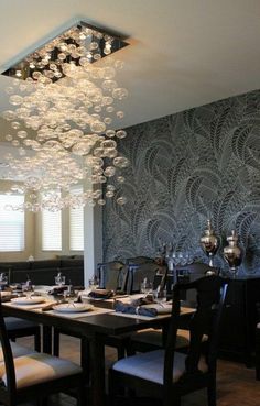 a dining room with a chandelier hanging from the ceiling and table set for four