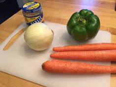 carrots, bell pepper, and garlic on a cutting board next to an onion