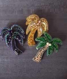 three brooches with palm trees on them