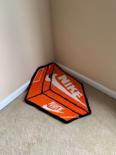 an orange and white kite laying on the floor in a corner with a wall behind it