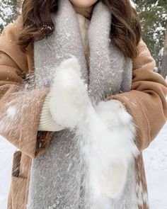 a woman standing in the snow with her hands on her chest and mittens over her face