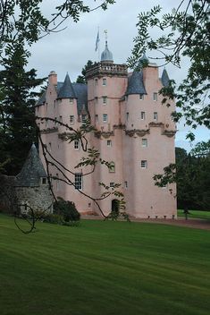 a large pink castle sitting on top of a lush green field