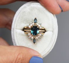 a woman's hand holding an engagement ring with blue and white stones