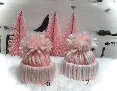 two pink knitted hats sitting on top of snow covered ground