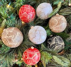 christmas ornaments hanging from the branches of a pine tree in red, white and gold