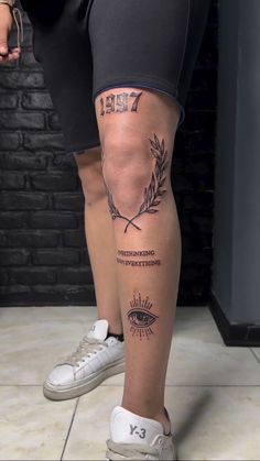 a woman's legs with tattoos on them and an eye in the middle of her leg