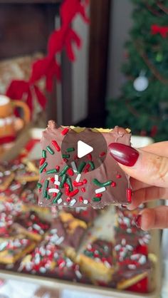 a person holding up a piece of chocolate with sprinkles