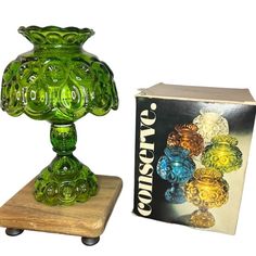 a green glass vase sitting on top of a wooden stand next to a box and package