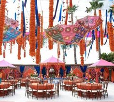 an outdoor dining area decorated with orange and blue decorations, hanging from the ceiling over tables