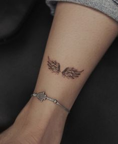 a woman's arm with an angel wing tattoo on the left side of her wrist