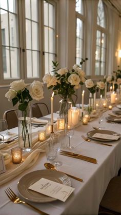 a long table is set with candles and flowers in vases, plates and silverware