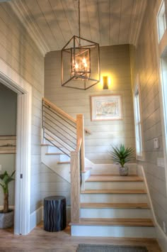 a hallway with stairs and a chandelier hanging from it's side wall