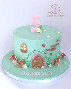 a green cake with flowers, mushrooms and a house on it's side that has the number one on top