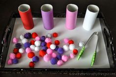 the tray is filled with different colored pom - poms and plastic cups on it