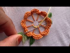 someone is working on an orange crochet flower