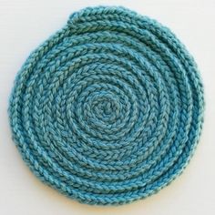 a close up of a knitted dishcloth on a white surface with blue yarn