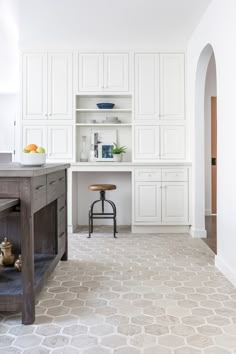 a kitchen with white cabinets and an island in the middle is seen from across the room