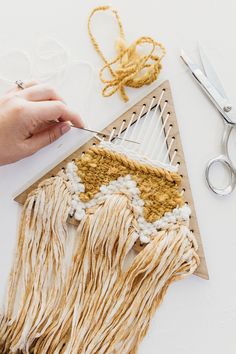 someone is working with yarn on a piece of wood and some scissors next to it