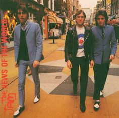 three young men walking down the street in suits and ties, one is wearing a blue jacket