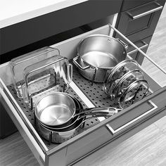 an open drawer with pots and pans on the bottom shelf in black and white