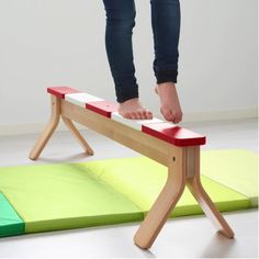 a person standing on top of a red and white bench next to a green mat