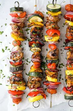 several skewers filled with different types of food on top of white parchment paper