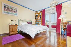 a bedroom with hardwood floors and red curtains on the windowsills is pictured in this image