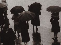 a group of people with umbrellas walking in the rain by the water's edge