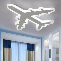 an airplane is flying in the sky above a bed and desk with blue curtains on it