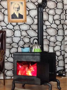 an old fashioned stove in front of a stone wall with a painting on the wall