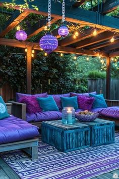 an outdoor living area with purple couches and lights