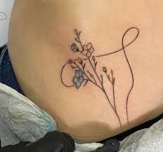 a woman's stomach has a tattoo with flowers on the side that says love