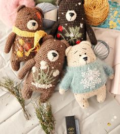 four crocheted teddy bears sitting on top of a table next to yarn balls