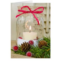 a glass jar with a candle and some pine cones