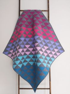 a blue and pink blanket sitting on top of a metal rack next to a white wall