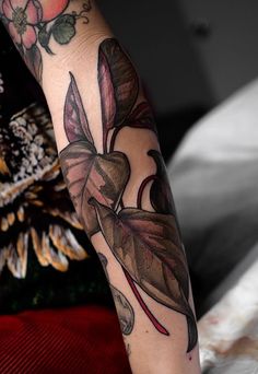 a woman's arm with flowers and leaves on it