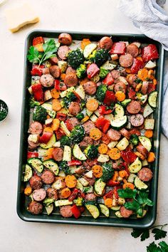 a pan filled with sausage and veggies on top of a table