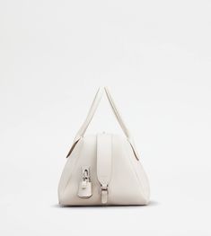 Characterized by maxi zip pulls, straps that elegantly cover the zip when closed, Tod's Darsena is defined by essential and feminine lines. Featuring characteristic tubular handles, it comes with the Tod's logo stamped on the front and a wrapped side padlock, a sophisticated distinctive trait. Here in fine natural-grained calfskin leather, this is a model with a distinctly urban nature, named after the city of Milan. Business Bags With Silver-tone Hardware In White, White Business Bags With Silver-tone Hardware, White Business Shoulder Bag With Palladium Hardware, White Shoulder Bag With Palladium Hardware For Business, White Evening Bag With Zipper Closure, White Formal Shoulder Bag With Zipper Closure, Formal White Shoulder Bag With Zipper Closure, Luxury Cream Bag With Zipper Closure, Luxury White Business Bags