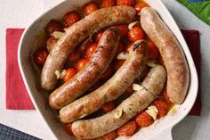 sausages and tomatoes in a white dish on a table