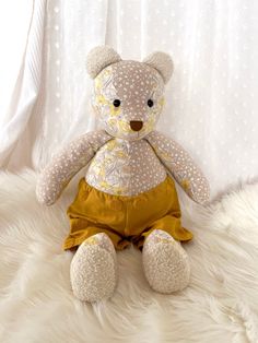 a teddy bear sitting on top of a white fur covered floor next to a curtain