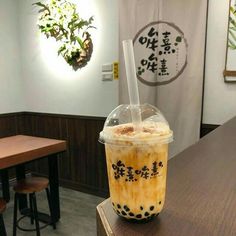 an iced coffee drink sitting on top of a wooden table in a restaurant or cafe