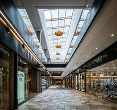 an empty shopping mall with lots of windows and lights above the store's shops