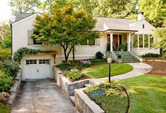 a white house with lots of trees and bushes around it's front entrance area