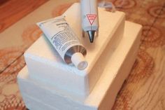 a pen and tube sitting on top of a small white box with some cream in it