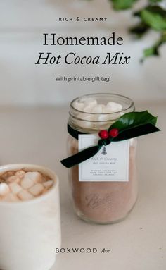 a cup of hot chocolate next to a jar with marshmallows in it