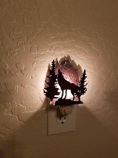 a night light with a wolf on it and some trees in the backround