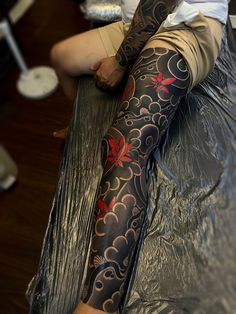 a man with a tattoo on his leg sitting on a table in front of a mirror